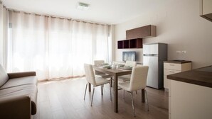 Una cocina moderna con comedor, sofá y un amplio ventanal con cortinas.