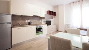 Una cocina moderna con refrigerador, horno y un comedor con mesa y sillas.