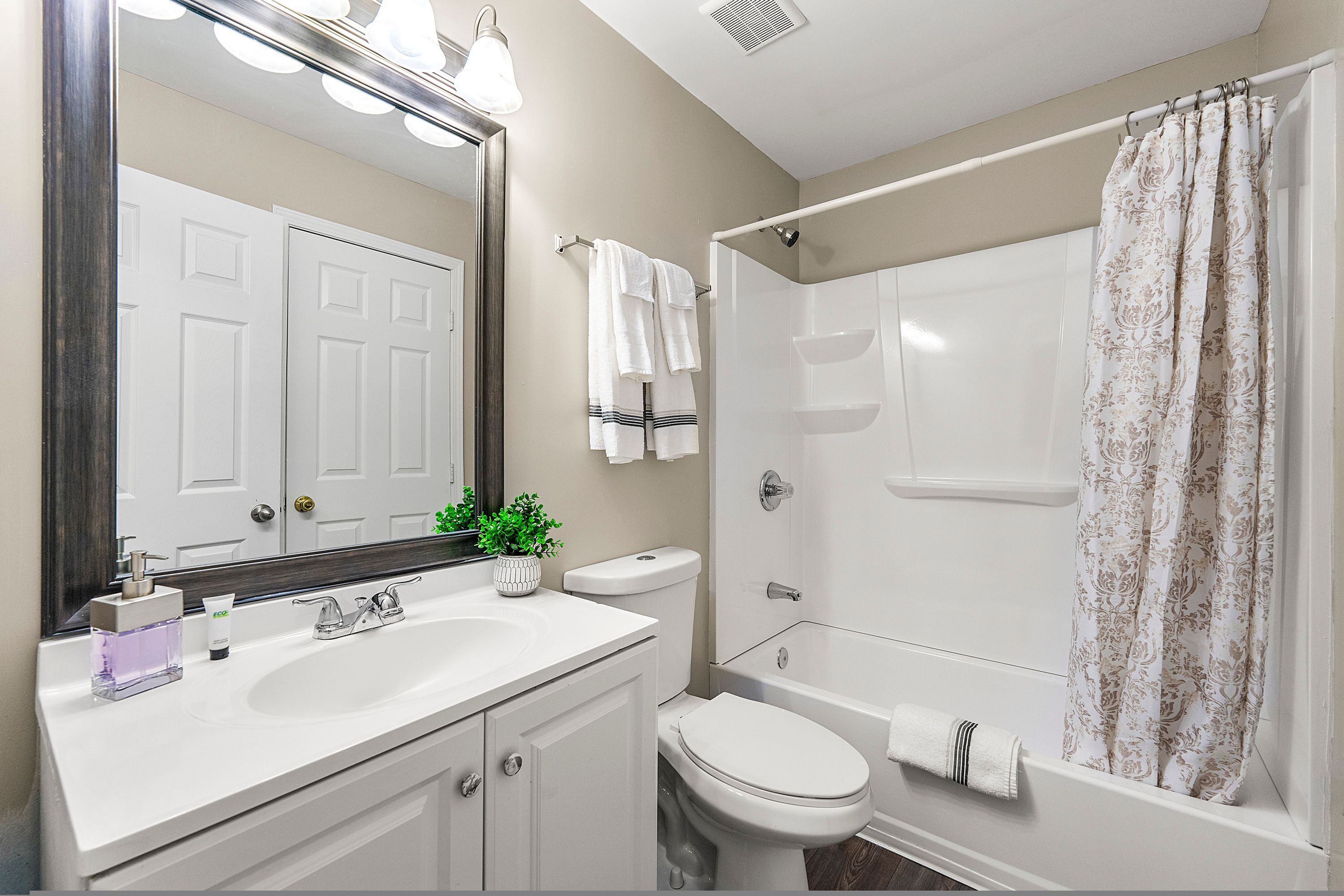A bathroom with a white sink, a toilet, a bathtub, and a shower curtain.
