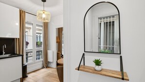 Uma cozinha moderna com bancada preta, luminária pendente e vista para a varanda.