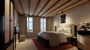 A bedroom with a large bed, wooden ceiling beams, a view through the window, and a wall-mounted artwork. - La Maison (Salzburg)