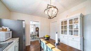 Eine Küche mit einem Edelstahl-Kühlschrank, einer Mikrowelle, einer Holz Arbeitsplatte, einer Kronleuchter und einem weißen Schrank mit Glastüren.