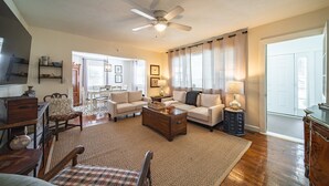 Ein geräumiges Wohnzimmer mit Deckenventilator, zwei Sofas, einem Couchtisch und einem Essbereich mit Tisch und Stühlen.
