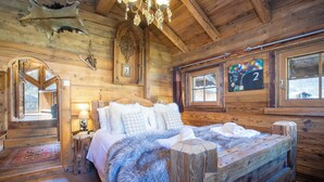 Ein Holzblockhaus-Innenraum mit einem Bett, einer Kristallleuchtre und der Nummer 2 an der Wand.
