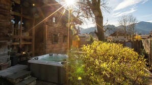 Eine Holzhütte mit Whirlpool, Steintreppe und Blick auf die Berge.