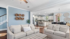 A spacious living room with a beige sofa set, a coffee table, and a patterned rug. - Walk to the Community Pool! 4 Bikes & Golf Cart! Book Today! - Shoreline at Highland Parks (Santa Rosa Beach)