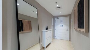 A hallway with a white door, a small cabinet, and a mirror on the wall. - Stayshort - Stylish 1BR Apartment With Stunning Lake Views (Dubai)