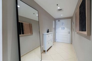 A hallway with a white door, a small cabinet, and a mirror on the wall. - Stayshort - Stylish 1BR Apartment With Stunning Lake Views (Dubai)