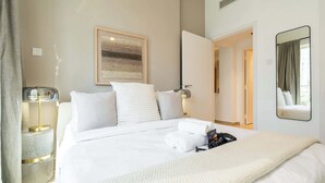 A neatly made bed with white linens, a bedside lamp, and a framed artwork on the wall. - Stayshort - Stylish 1BR Apartment With Stunning Lake Views (Dubai)