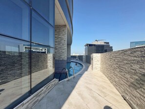 A rooftop pool area with a clear view of the city skyline, modern architecture, and a pool with a metal ladder. - Stayshort - Stylish 1BR Apartment With Stunning Lake Views (Dubai)