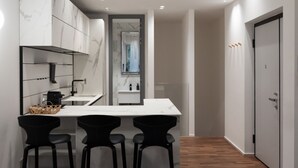 A modern kitchen with a marble backsplash, a central island with bar stools, and a view into the adjacent bathroom. - Refined two-room bedroom between Brera and the Duomo (Milan)