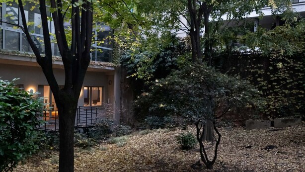 An outdoor courtyard with a tree, a stone pathway, and a building with large windows. - Refined two-room bedroom between Brera and the Duomo (Milan)