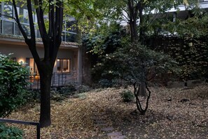 An outdoor courtyard with a tree, a stone pathway, and a building with large windows. - Refined two-room bedroom between Brera and the Duomo (Milan)