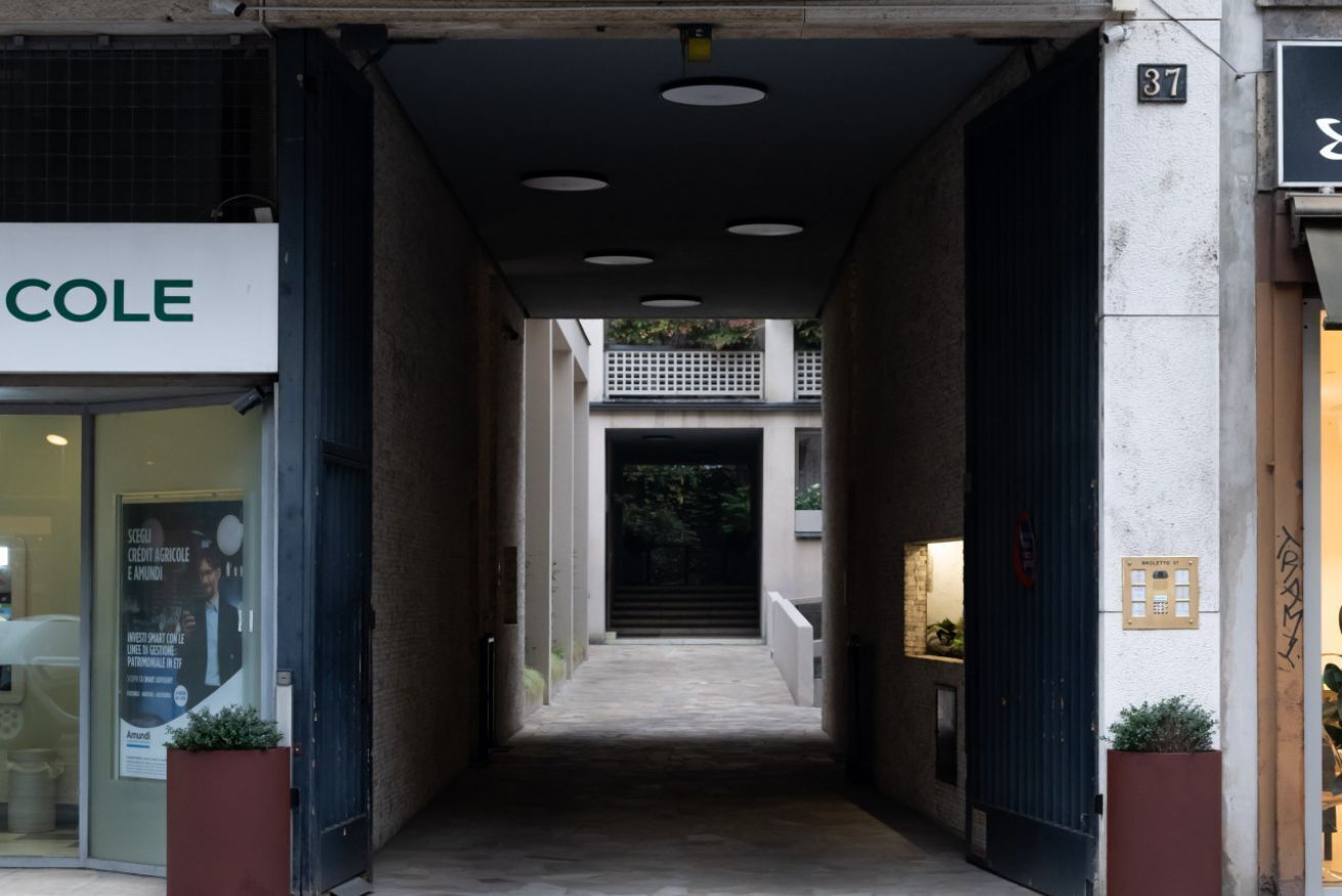 Un couloir étroit, avec une vitrine sur le côté gauche et une porte sur le côté droit.