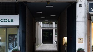 A narrow hallway with a storefront on the left and a door on the right. - Refined two-room bedroom between Brera and the Duomo (Milan)