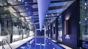 A modern indoor swimming pool with glass walls, benches, and a clear ceiling. - City Stay Steps From Yarra River Walks (Melbourne)