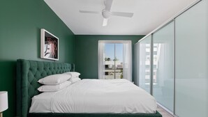 A bedroom with a green upholstered headboard, a white bedspread, and a ceiling fan. - Bright Stay in Sydney With Harbour Bridge Views (Sydney)