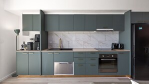 A modern kitchen with teal cabinets, a stainless steel dishwasher, and a black refrigerator. - Bright Stay in Sydney With Harbour Bridge Views (Sydney)