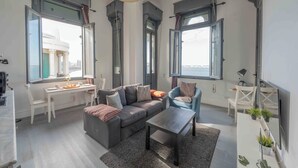 A modern living room with a grey sofa, a coffee table, and a dining area with a white table and chairs. - Grey l studio apartments Corniche Alexandria Little Venice (Alexandria)
