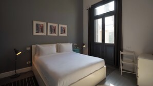 A bedroom with a large bed, a desk, and a chair. There are three framed pictures on the wall. - Grey l studio apartments Corniche Alexandria Little Venice (Alexandria)