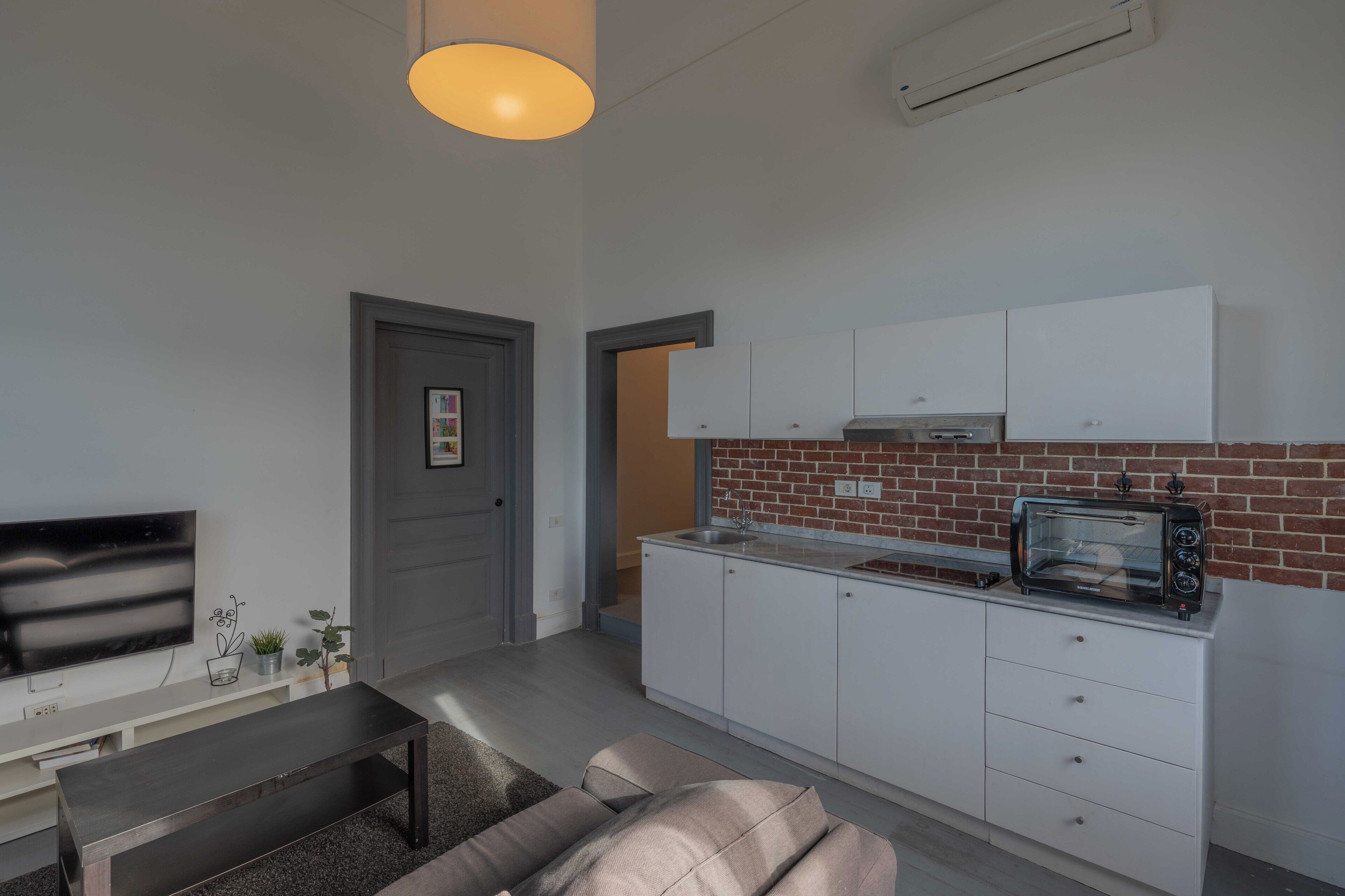 A modern kitchen with white cabinets, a built-in oven, and a toaster.