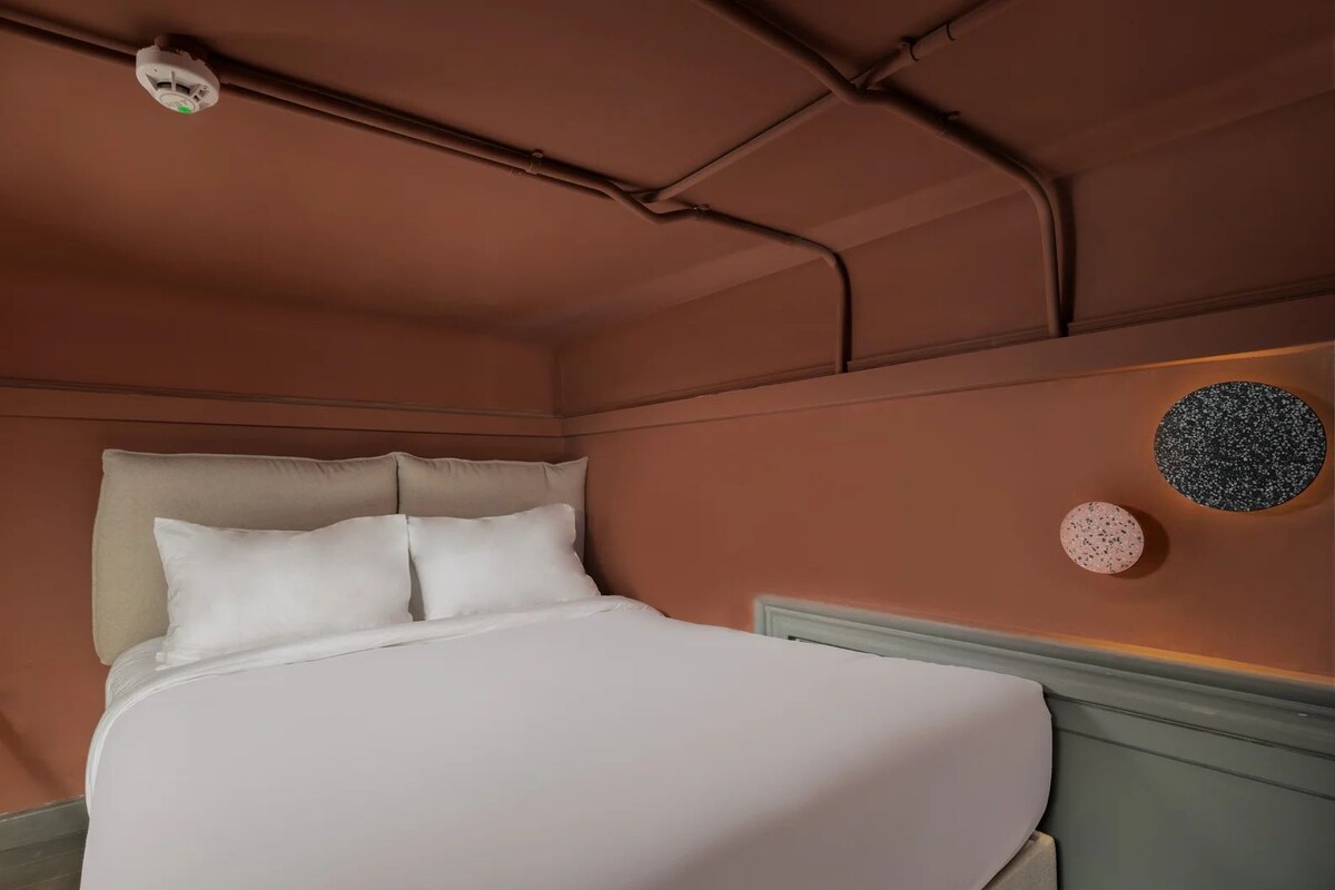 Ein Bett mit Kopfteil, einer Wandleuchte und zwei Wandbildern.