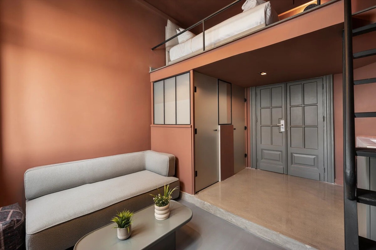 Ein modernes Interieur mit einer Couch, einem kleinen Tisch mit Pflanzen, einer Tür und einer Treppe.