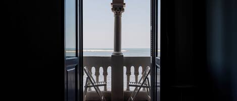 An open doorway leading to a balcony with a checkered floor and two chairs.