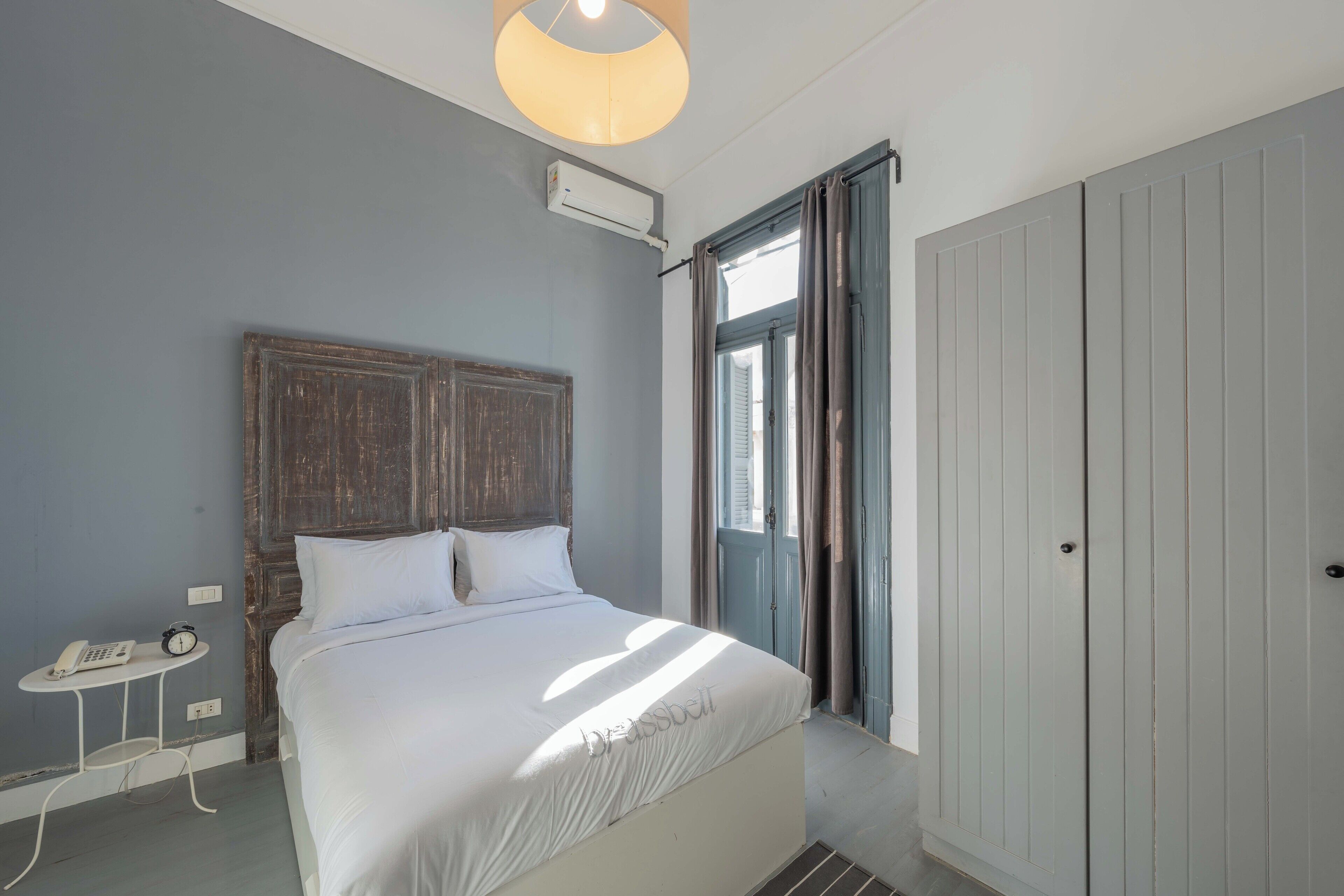 A bedroom with a bed, bedside table, and an air conditioning unit.