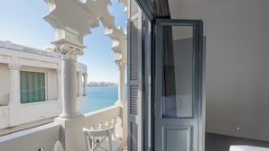 A balcony with white columns, a view of the sea, and a cityscape in the background. - Grey l studio apartments Corniche Alexandria Little Venice (Alexandria)