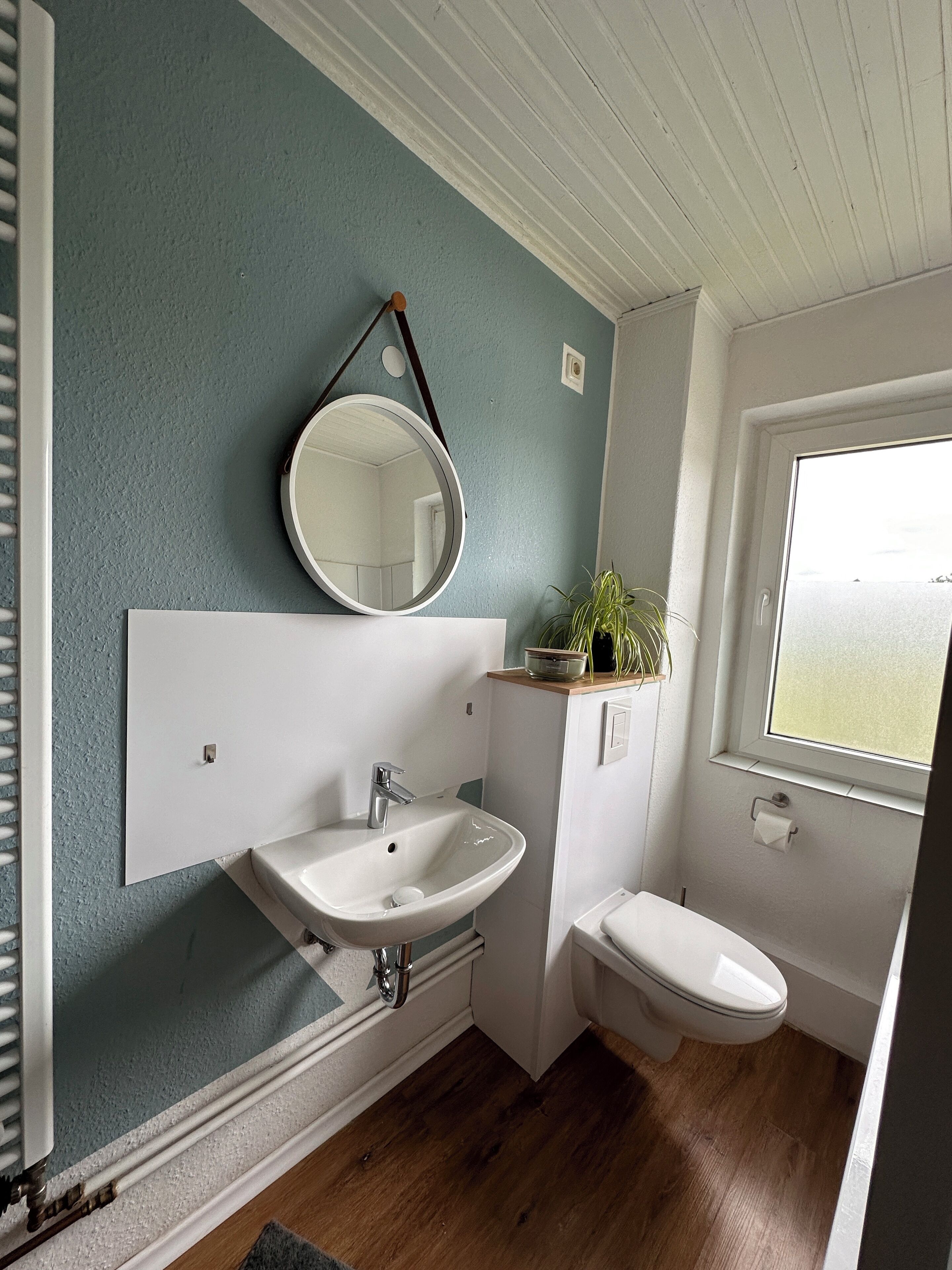 A bathroom with a white sink, a mirror, and a toilet.