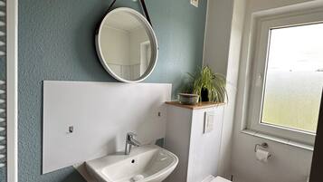 A bathroom with a white sink, a mirror, and a toilet.