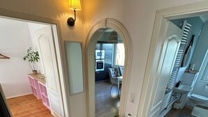 A hallway with a patterned rug, a small table with a plant, and an archway leading to a dining area with a chair and table. - House Königsee *garden view (Bad Oldesloe)