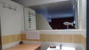 Ein Badezimmer mit einer Holzbank, einem Waschbecken und einem Spiegel.