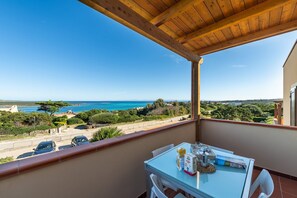 Een balkon met een ontbijttafel en uitzicht op de kust.