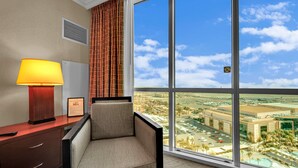 Hotellihuone, jossa on suuri ikkuna, työpöytä lampun kanssa ja tuoli.