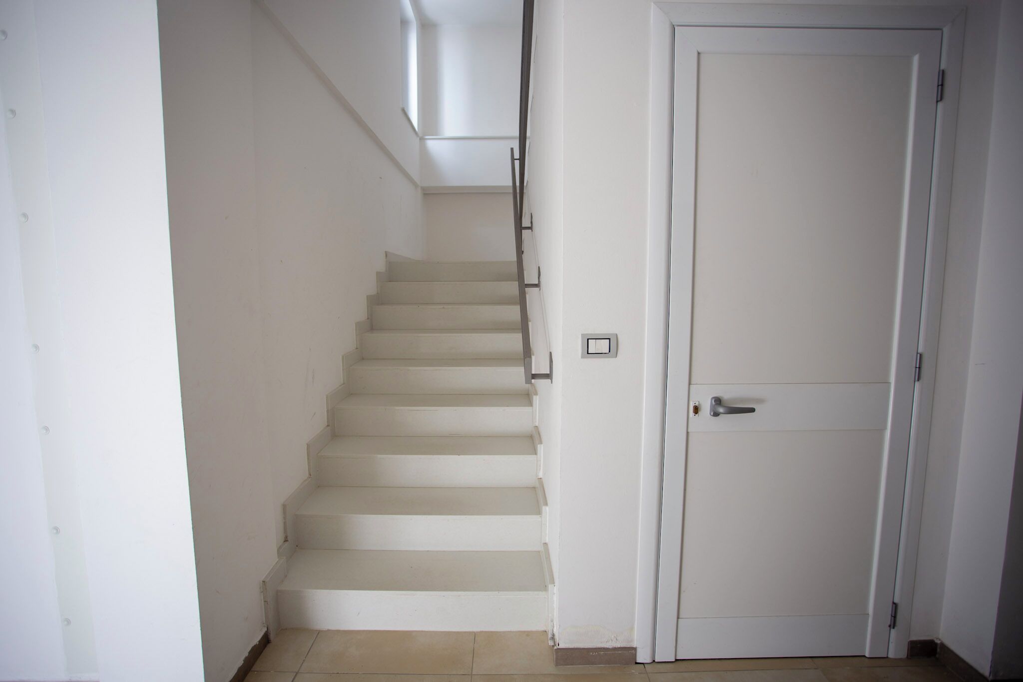 A staircase leading to a door with a light switch on the wall.