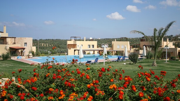Un complexe hôtelier doté d’une piscine, de chaises longues et offrant une vue sur le paysage environnant.