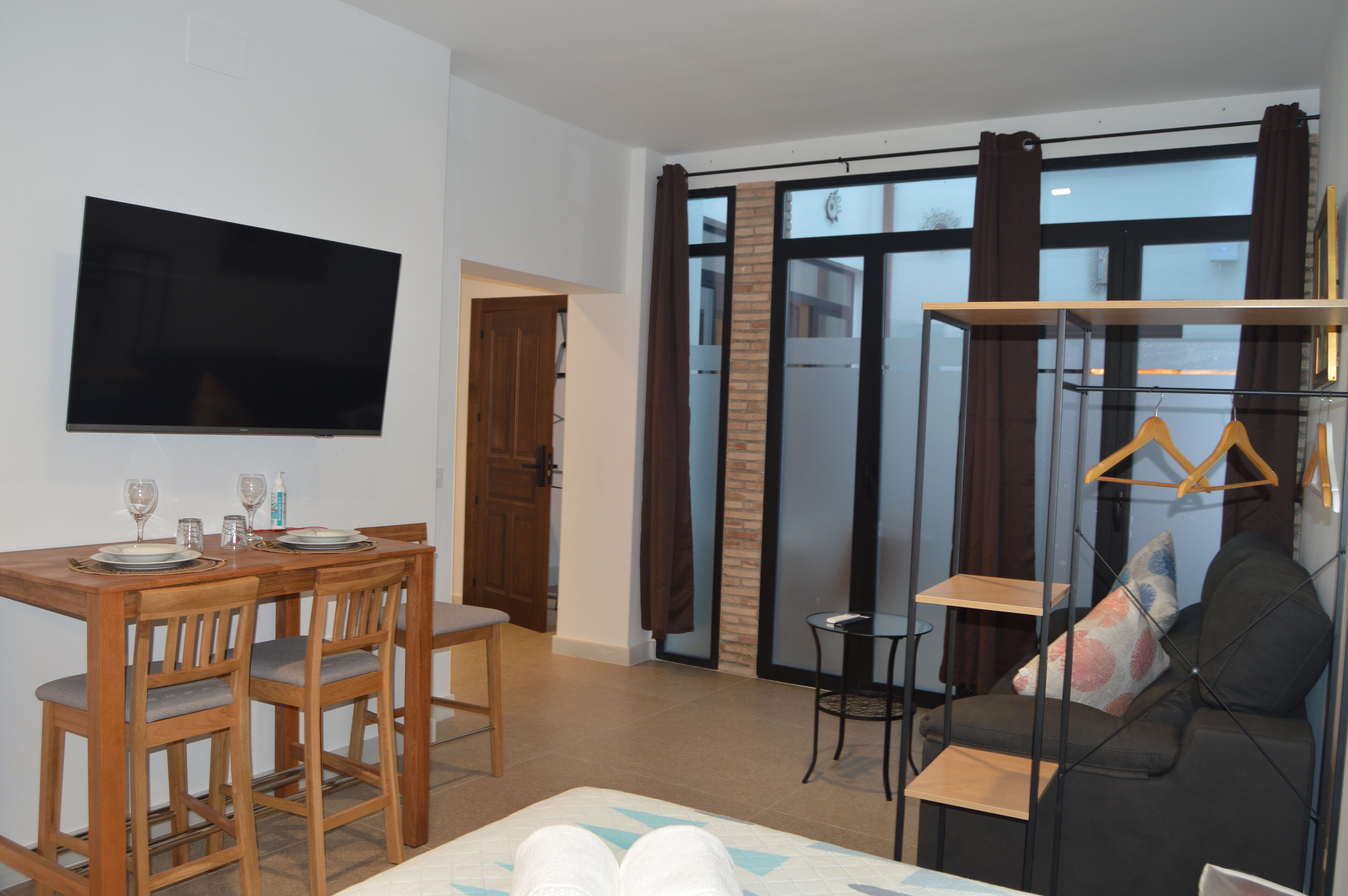 Ein modernes Wohnzimmer mit Flachbildfernseher, Esstisch aus Holz und einer Couch.