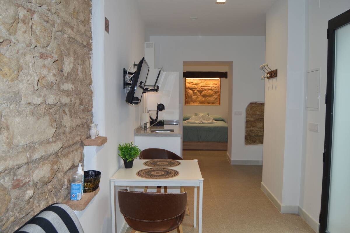 A compact living space with a kitchenette, a dining area, and a bedroom.