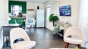 Une cuisine moderne avec des meubles de couleur verte, un réfrigérateur blanc et un coin repas comprenant deux chaises et une table.
