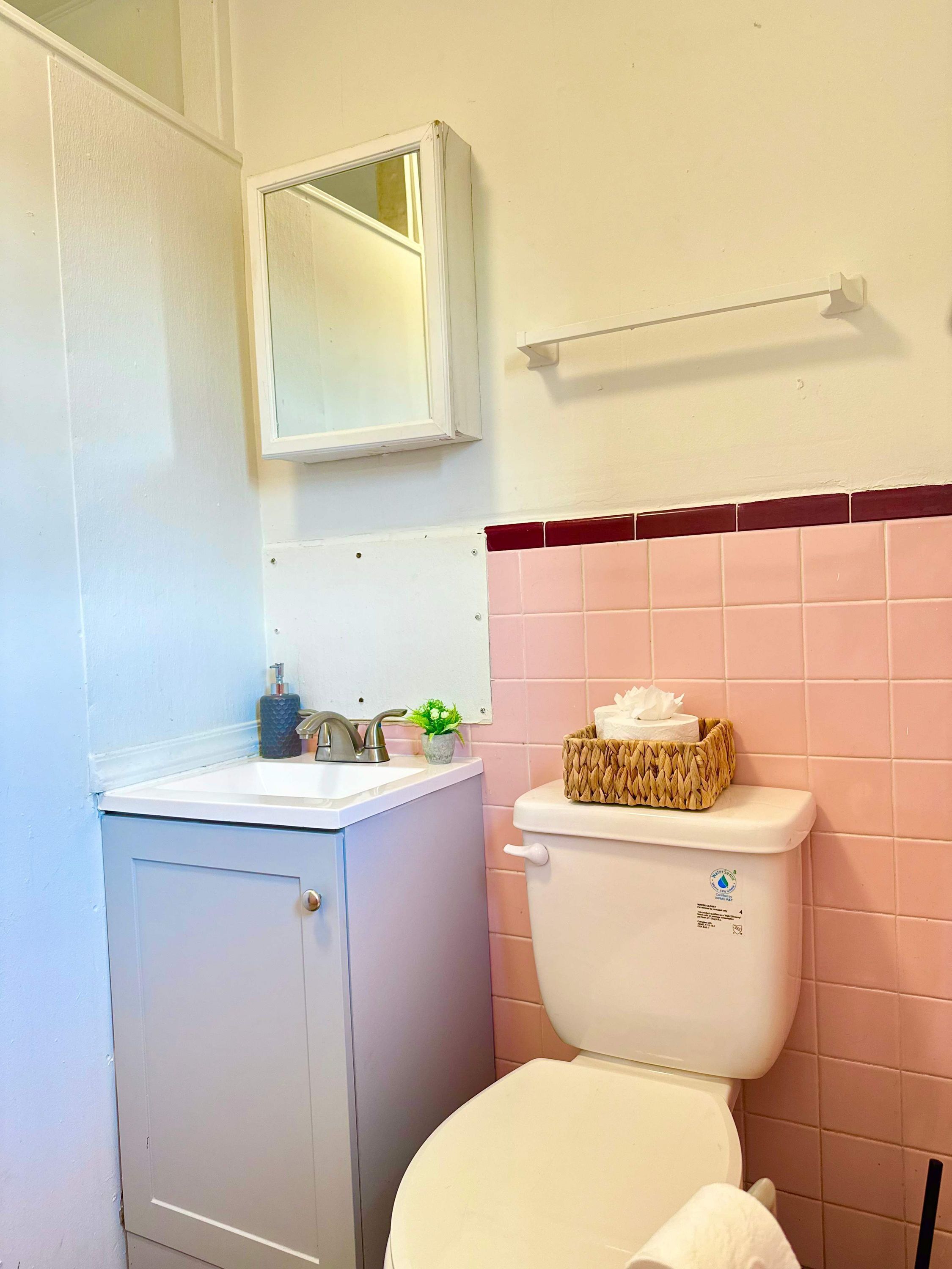 Une salle de bain avec un lavabo blanc, un miroir, des toilettes et un porte-serviettes.