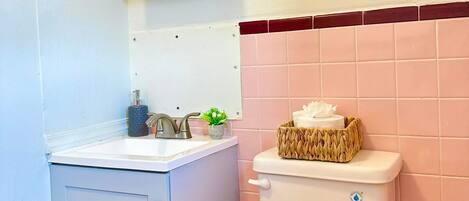 Une salle de bain avec un lavabo blanc, un miroir, des toilettes et un porte-serviettes.
