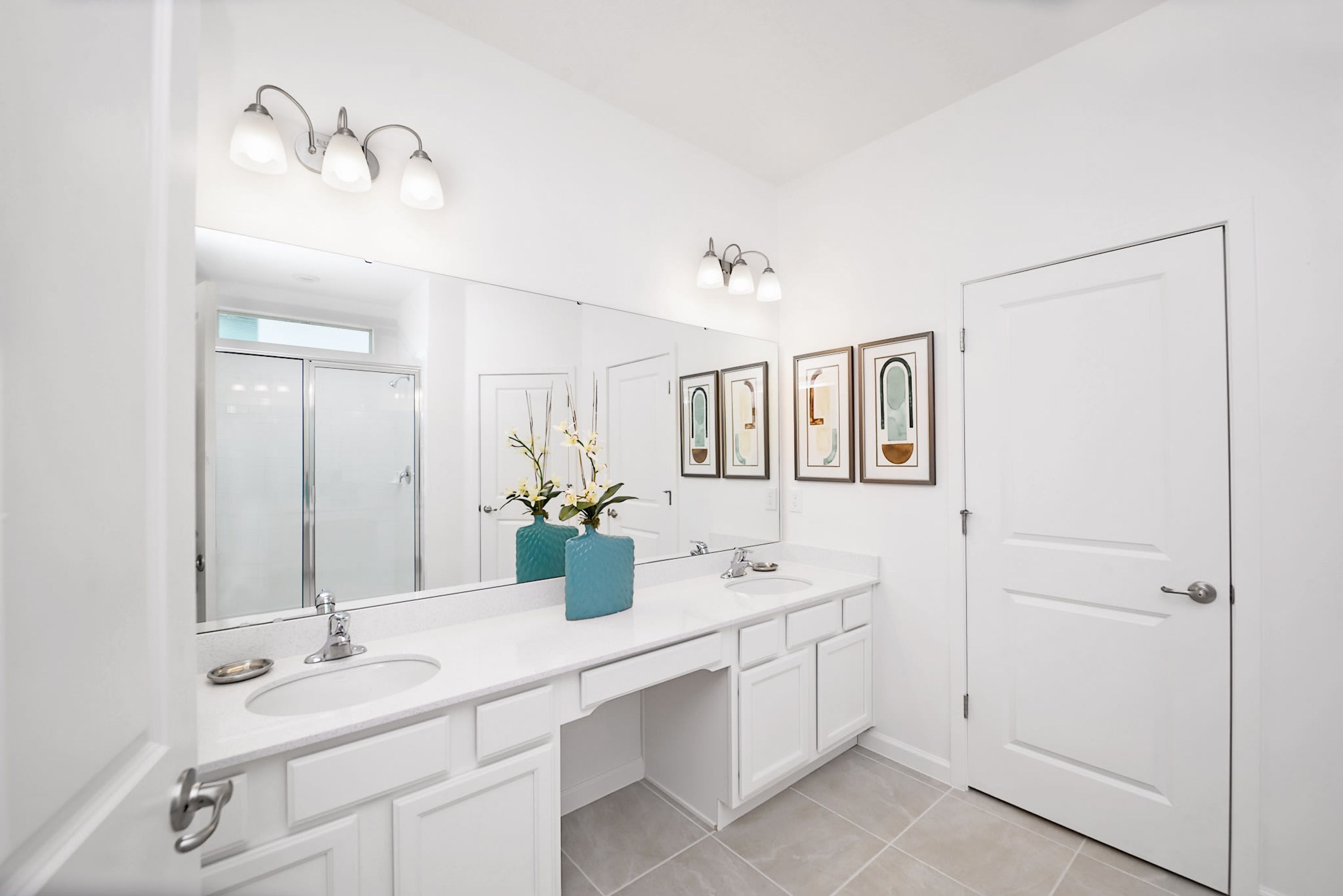 A modern bathroom with a white vanity, a large mirror, and three wall-mounted lights.