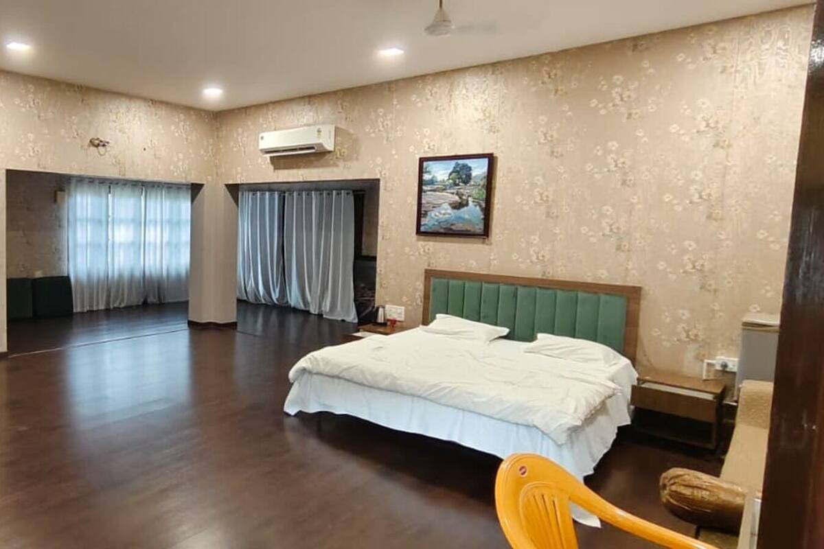 Ein geräumiges Hotelzimmer mit einem großen Bett, einem Kleiderschrank, einem Spiegel und einem Badezimmer mit Dusche und Toilette.