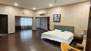 A hotel room with a large bed, a wardrobe, a bathroom with a shower, and a balcony with curtains. - ND Film City and Heritage Theme Resort (Khalapur)