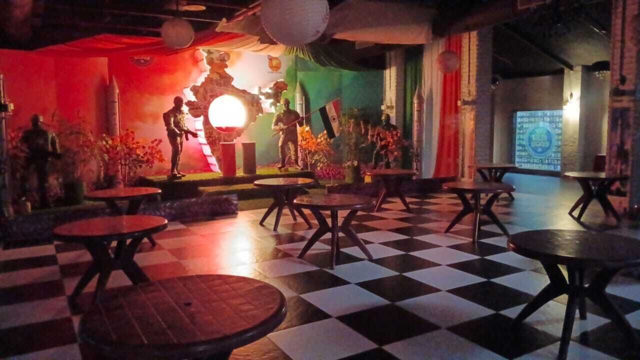A checkered floor with round tables and chairs, a stage with a flag, and a wall with a poster.