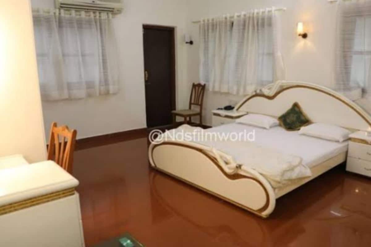 Un dormitorio con una cama, una silla, una mesita de noche y una mesita auxiliar.