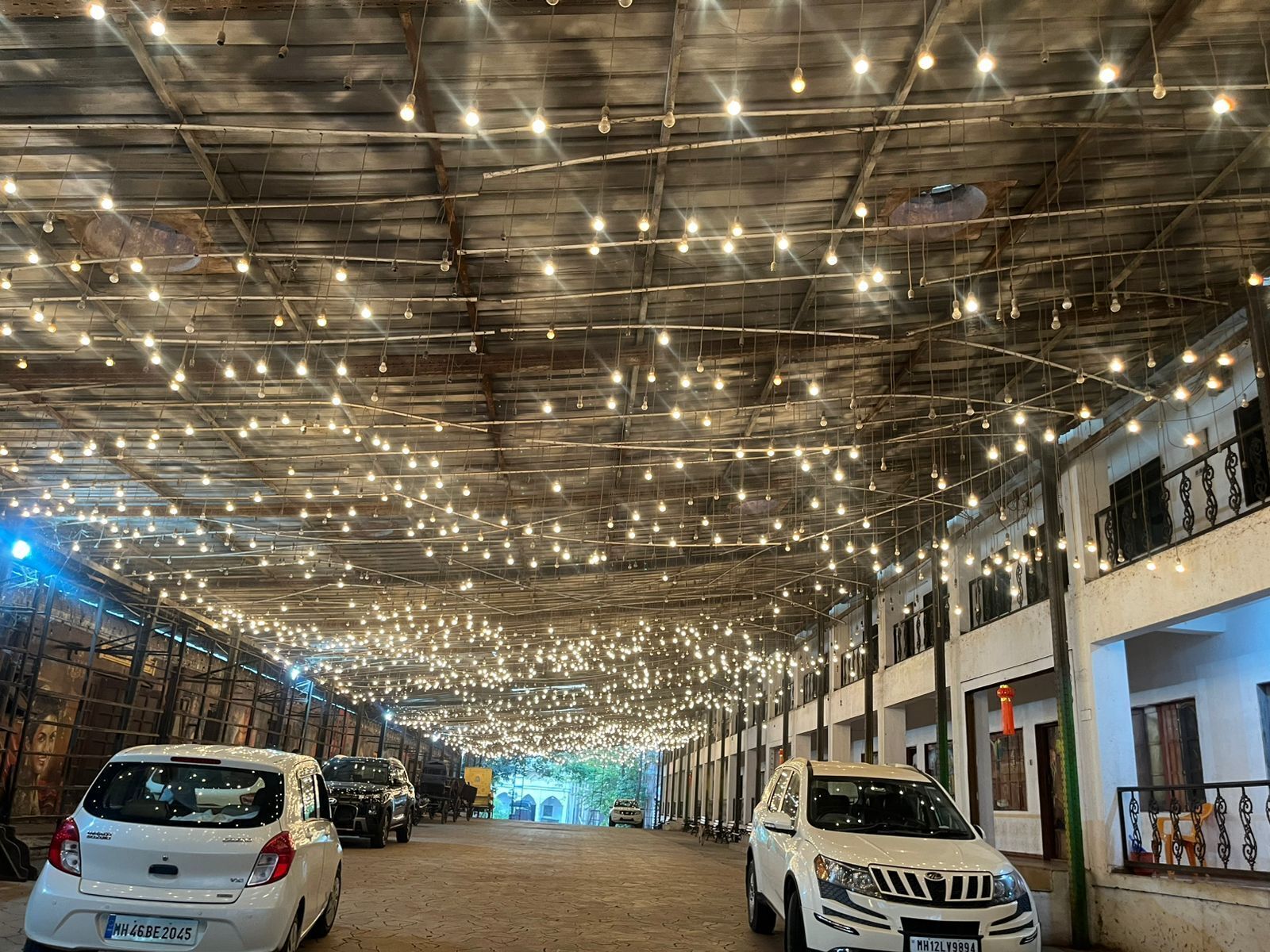 Un'ampia area interna con soffitto alto decorato da numerose luci a sospensione. Diversi veicoli sono parcheggiati lungo i lati, e le pareti sono fiancheggiate da finestre.