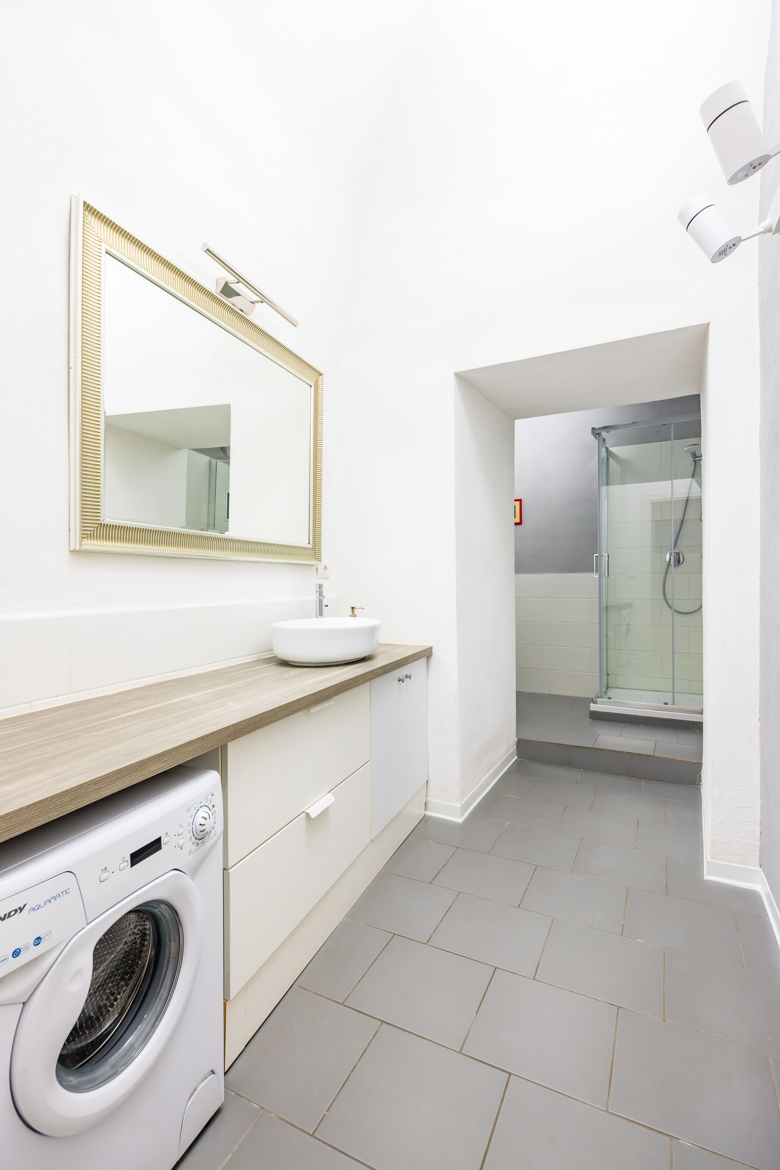 Un baño moderno con lavamanos, espejo y cabina de ducha de vidrio.